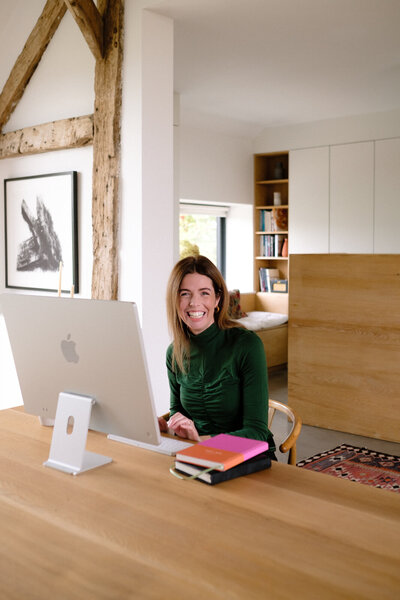 A woman sitting at a desk, focused on her work with a laptop and notepad in front of her.
