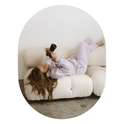 Minnesota wedding photographer examines the photos she just took on her camera while laying on comfy white couch in St. Paul photography studio