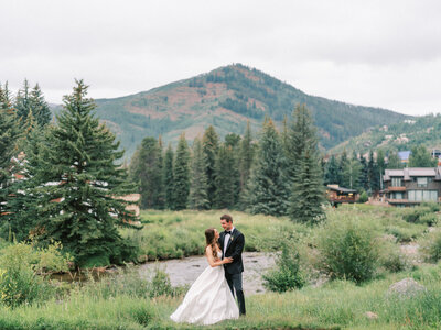 Bride and groom standing in front of a mountain landscape