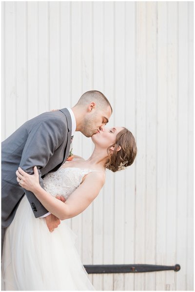 Bride and Groom kissing as groom dips back his bride and they hug tightly.