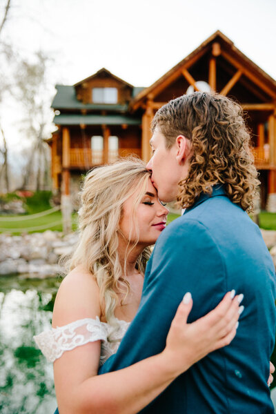 Jackson Hole videographer captures bride and groom hugging while groom kisses bride's forehead