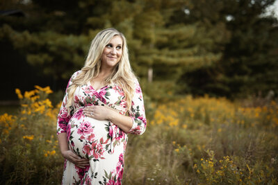 Maternity photo of mom in red dress in winter pine trees