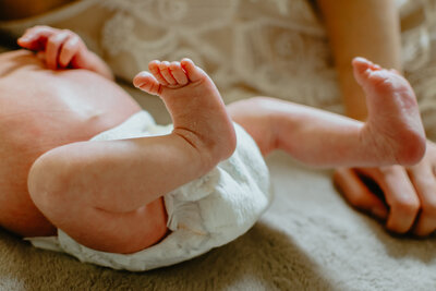 In-Home Newborn Photography - baby laying on bed showing baby feet and baby toes, diaper, and legs