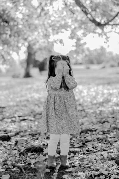 A little girl covers her eyes playfully during her Richmond fall family photo session. 