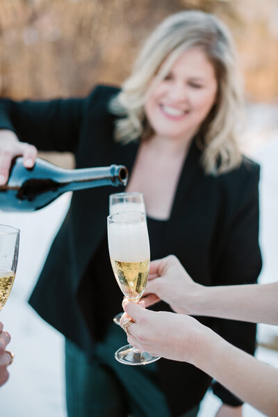 Woman smiles and pours champagne into glasses