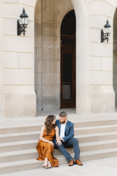 couple sitting on steps of classic architecture building during engagement session
