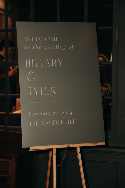 Welcome to our wedding sign in dark green and gold. Positioned on easel for wedding at The Vanderbilt