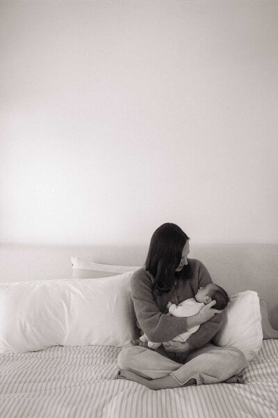 Mother holding newborn baby on a couch during newborn photography session