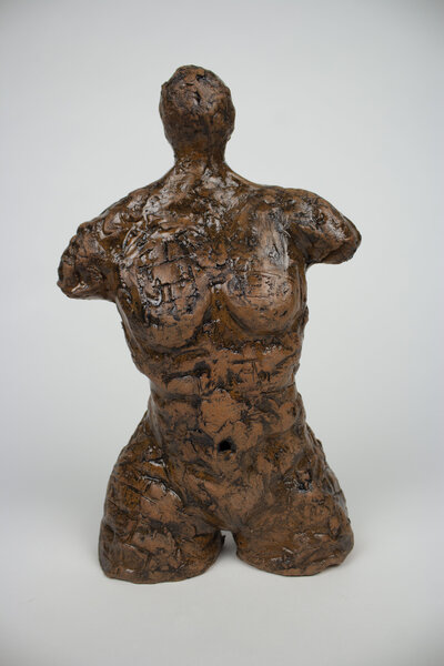 A ceramic bust of a feminine body with various cracks and brick textures