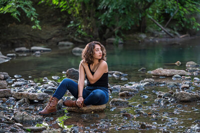 A dark and dramatic photograph of a high school senior in a creek in Palatine.
