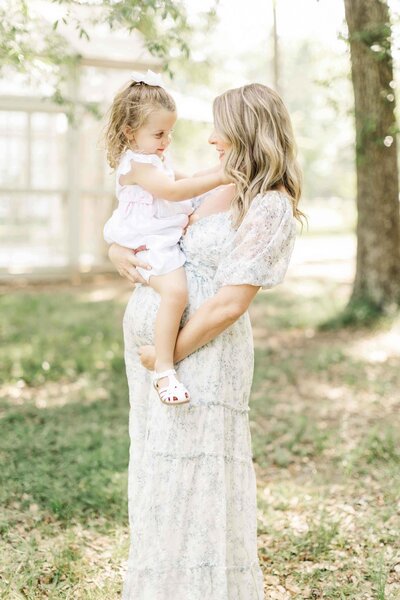 expecting mama holds toddler ontop of her belly for family photography