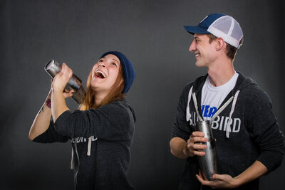 Branding photo of two bar tenders laughing and making drinks