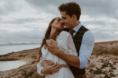 Bride and groom embracing on California beach