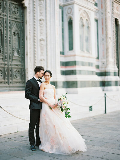 A groom stands behind his bride outside of the Duomo in Florence, Italy