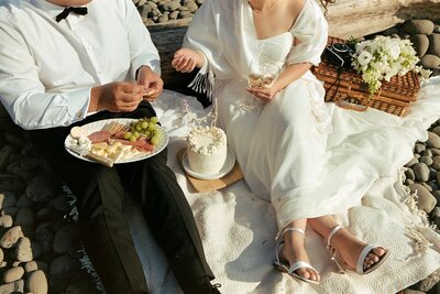 An eloping couple eating a picnic on the beach on 35mm film