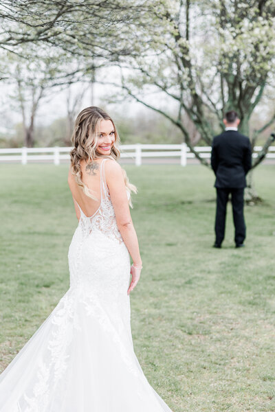 bride smiling playfully as groom waits with back turned to her