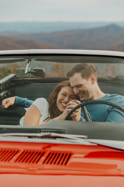 photo of adventurous couple holding hands in vintage car on the blue ridge parkway