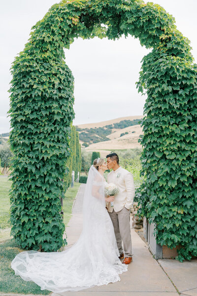 Bride and groom under a beautiful arch of greens