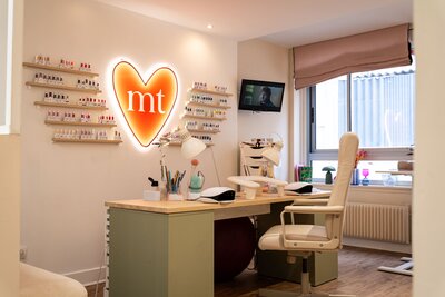 Espace onglerie de Maison Tokama à Rennes, avec vernithèque colorée et poste de travail soigné pour la beauté des ongles, fauteuil confortable.