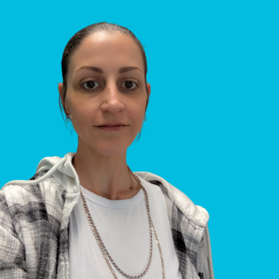 woman Housing and Outreach Program Manager at Move Forward with dark hair in black and white plaid shirt with blue background