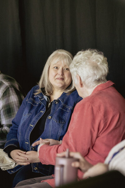 Two older ladies enjoying a conversation and smiling 