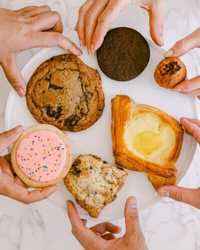 Creative colorful product photography for bakery pastry shop. Hands grabbing pastries.
