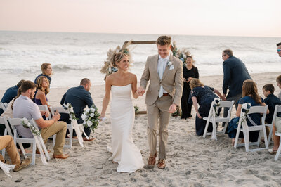 A bride and groom hold hands in the air as the walk through a sparkler send off at the end of their wedding reception.