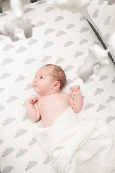 Baby in crib with mobile above