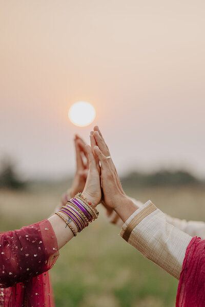 Bride and groom with hands together as sunsets behind them during a traditional indian ceremony