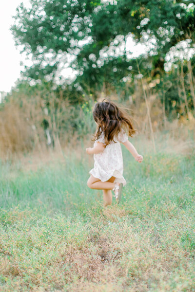 candid photo of toddler running through a field of grass
