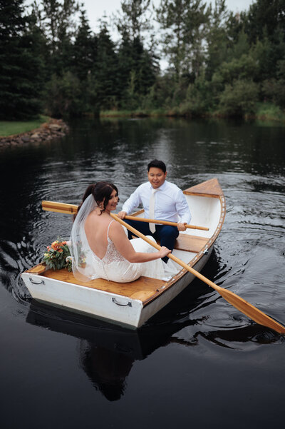 Pine and Pond Wedding Venue Couple in a rowboat Alberta wedding