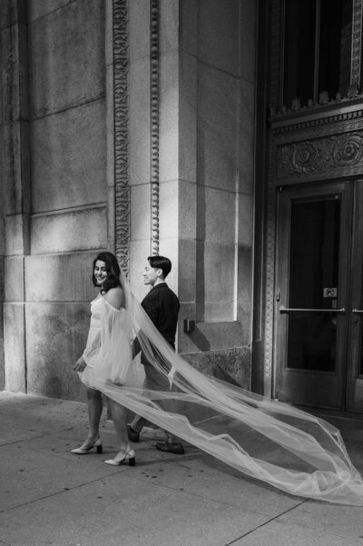 Bride leads groom in front of the Chicago City Hall