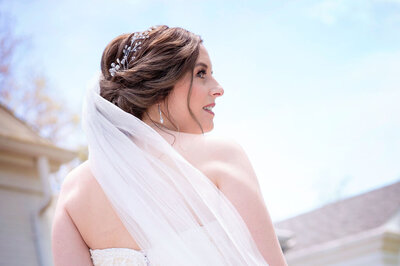 Bride smiles over her shoulder with her veil blowing behind her