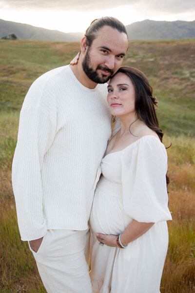 Couple standing together while woman holds pregnant belly | California Maternity Session