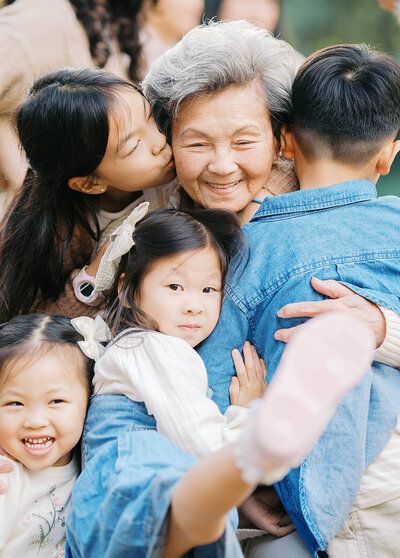 Candid backyard family photo of a happy grandma embracing in a big hug with all her grandchildren 