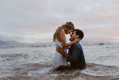 Woman kneeling holding man in water