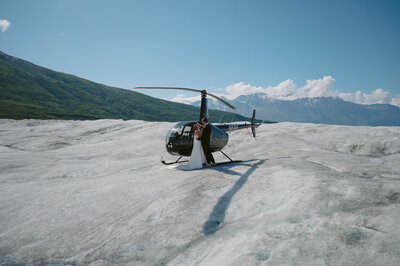 alaska elopement couple stand front of helicopter