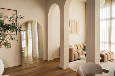 Uitzicht door de elegante bogen op de woonkamersetting in Studio Laurant, met daglichtstralen die de ruimte sfeervol verlichten.