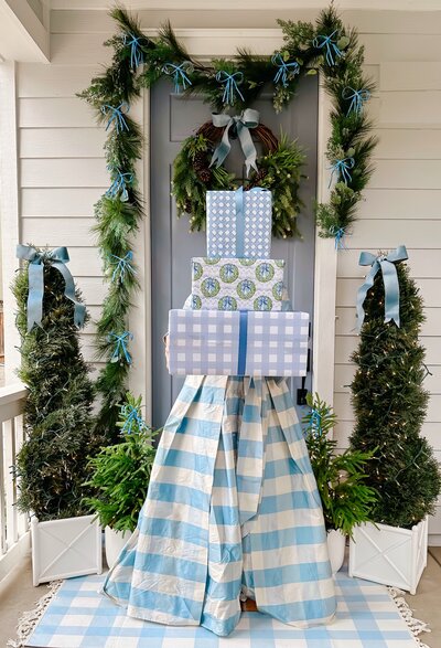 a front porch decorated with trees and a wreath