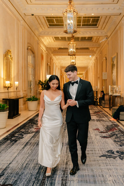 picture of bride and groom walking down a hallway while smiling and holding hands taken by Palm Springs desert wedding photographer