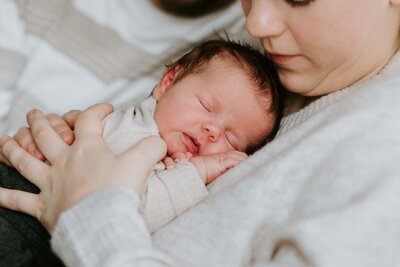 Ein Neugeborenes Baby liegt auf der Brust der Mutter beim Foto Shooting mit Sarah Thelen