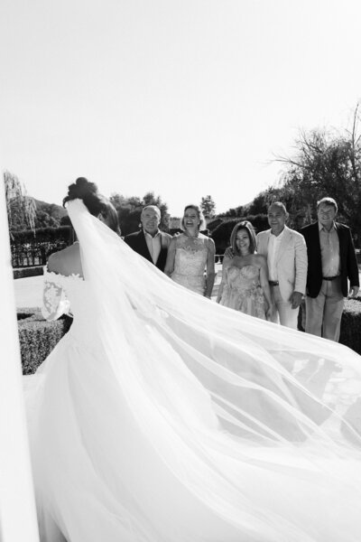 Bride has a first look with her parents and in-laws with her veil blowing in the wind at this intimate wedding at a private estate in Temecula, California,