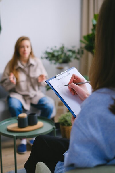 Woman speaking to another and writing in a notebook