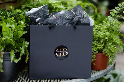 Black gift bag with black tissue paper and the initials GB