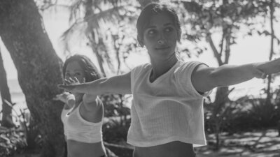 Black and white photo of blonde, female yoga instructor smiling at the camera.