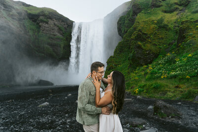 couple embraces each other in front of Skogafoss in iceland during their international adventure elopement