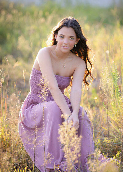 senior photo shoot of brunette in a field of wildflowers locted in moss park, orlando, florida