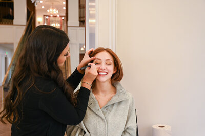 Victoria applying eyeliner to woman
