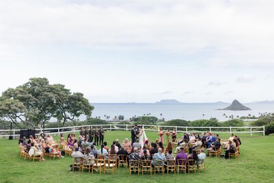 A couple standing in the middle of a semi-circle of their guests as they say their vows at their wedding 