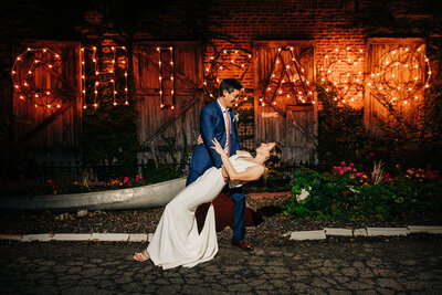 Groom playfully dips bride while dancing in front of "Chicago" lit up sign